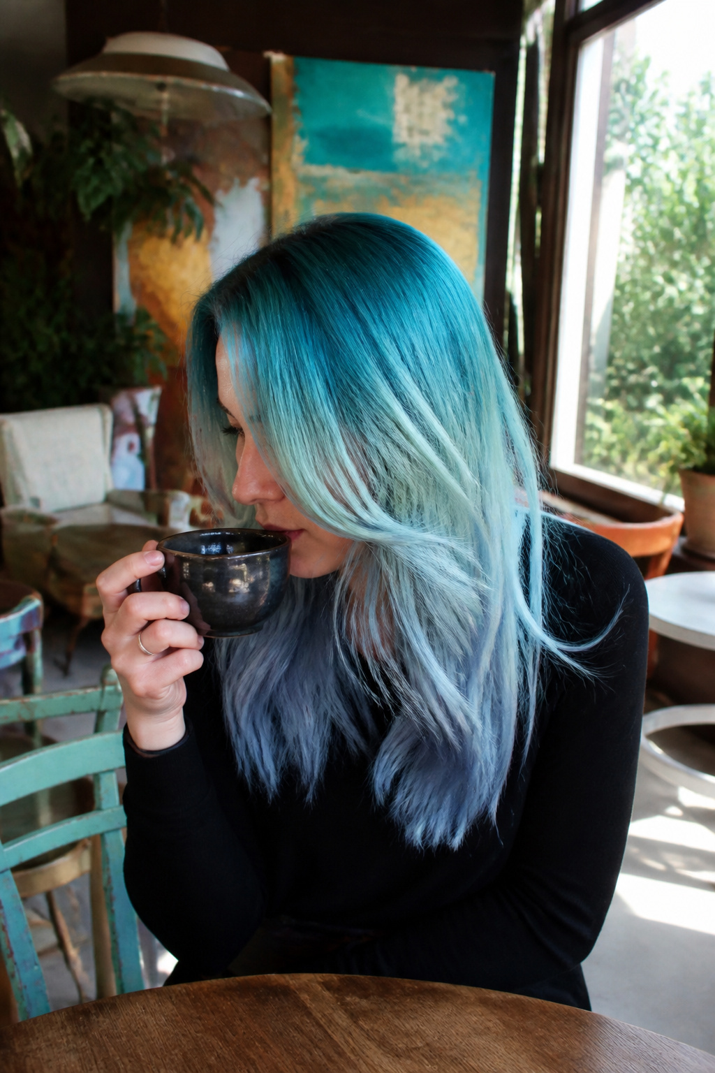 Best Holographic Hair Ideas: Colors, Styles and Techniques for 2026 10 Model with teal roots and blue ends in a cozy coffee shop.