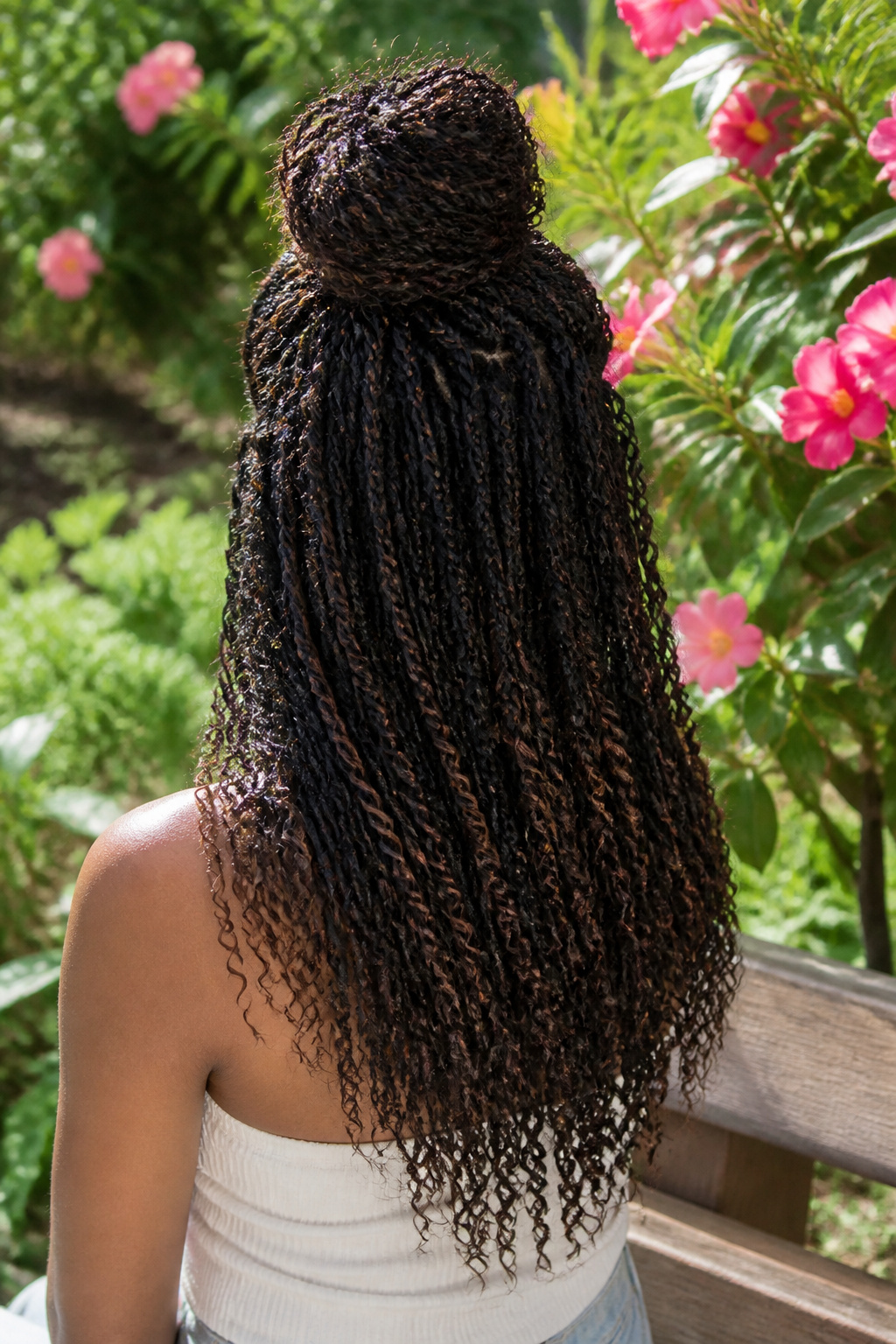 15 Crochet Braids Styles for 2026: From Box Braids to Butterfly Locs 11 Model showcasing a half-up half-down crochet braids style surrounded by flowers.