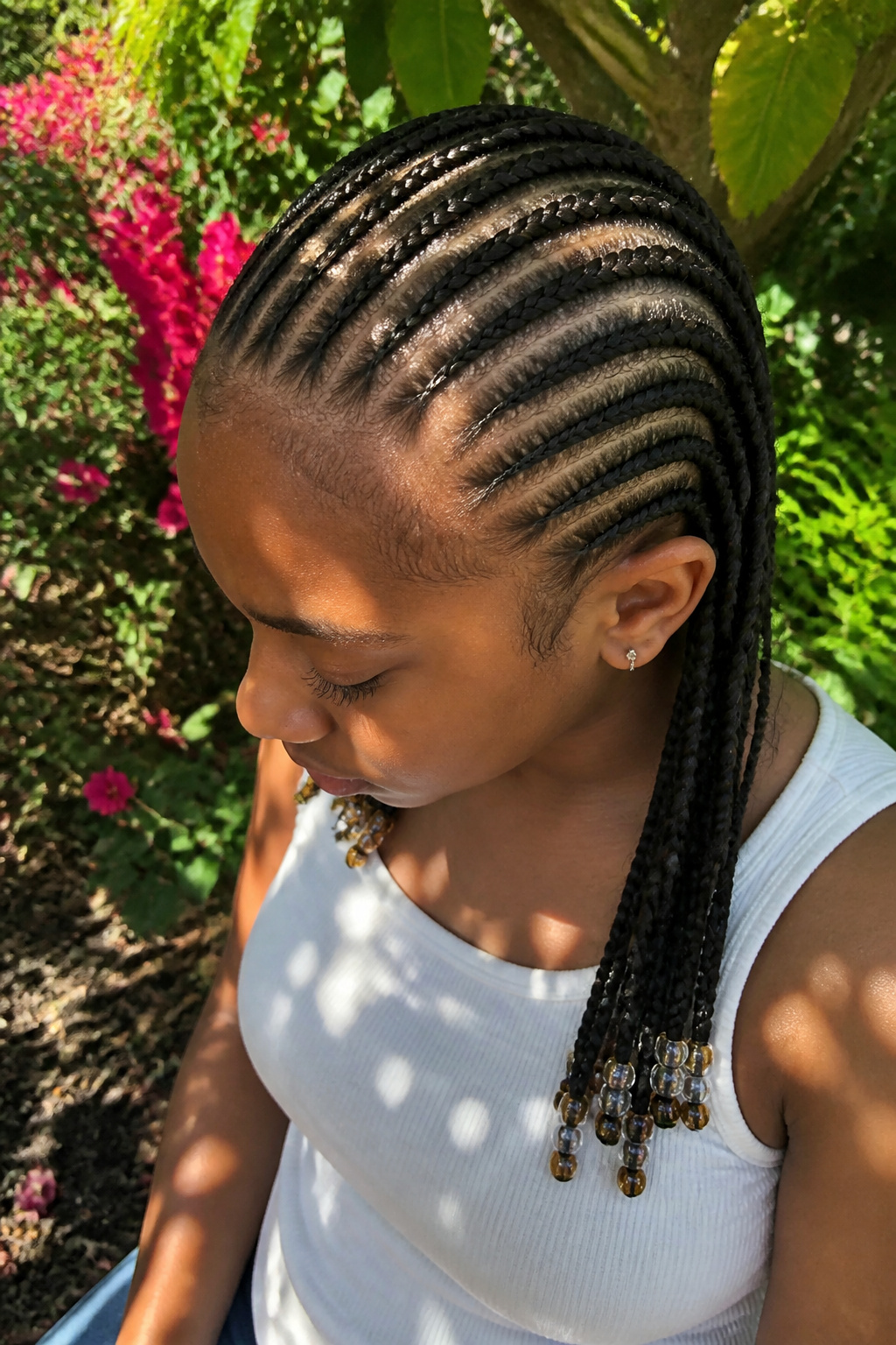 A Black girl showcasing her cornrows in a vibrant garden.