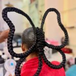 Intricate black braided hair styled into a large butterfly shape on a person